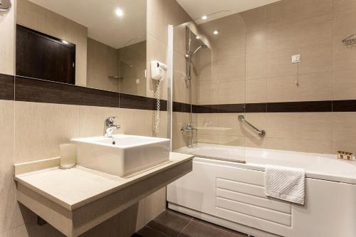 a bathroom with a sink and a bath tub and a sink at Sofia Palace Hotel by HMG in Sofia