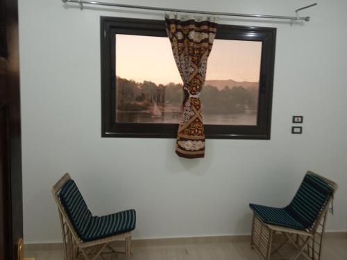 two chairs and a window with a curtain at ABAZIDO Nubian Guest House in Aswan