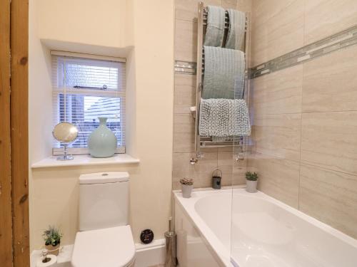 ein Bad mit einem WC, einer Badewanne und einem Fenster in der Unterkunft Milford Cottage in Belper