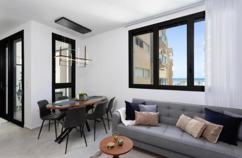 a living room with a gray couch and a table at Sea View 2 BR near Shouk Hacarmel by HolyGuest in Tel Aviv