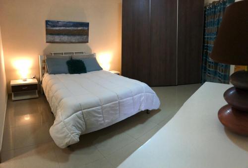 a bedroom with a large white bed and two lamps at The Village Apartment 2 in Kirkop