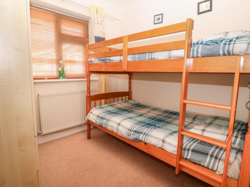 a bedroom with two bunk beds and a window at Seagull Cottage in Holyhead