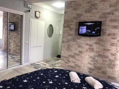 Cette chambre dispose d'une télévision sur un mur en pierre. dans l'établissement Апартаменты Дворец Украины с круглой кроватью, à Kiev