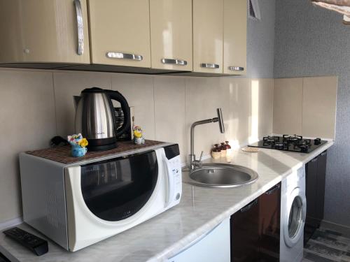 uma cozinha com um micro-ondas e um lavatório em Апартаменты Дворец Украины с круглой кроватью em Kiev