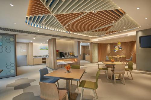 a lobby with tables and chairs and a kitchen at Holiday Inn Express Nantong Textile City by IHG in Tongzhou