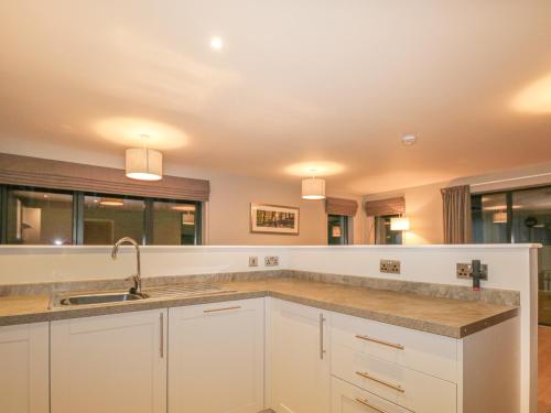 a kitchen with white cabinets and a sink at Otter Lodge in Kingussie