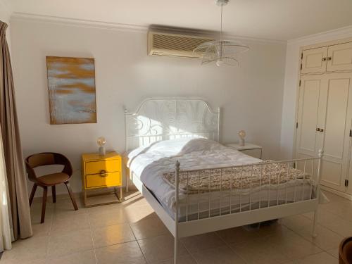 1 dormitorio con 1 cama blanca y 1 silla en Seaside doors en Vila Real de Santo António