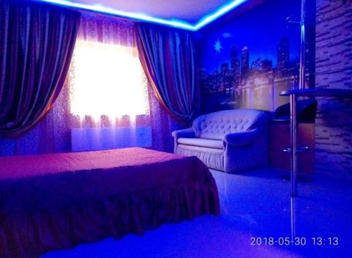 a bedroom with a bed and a chair and a window at Апартаменты Голубая Лагуна in Kharkiv