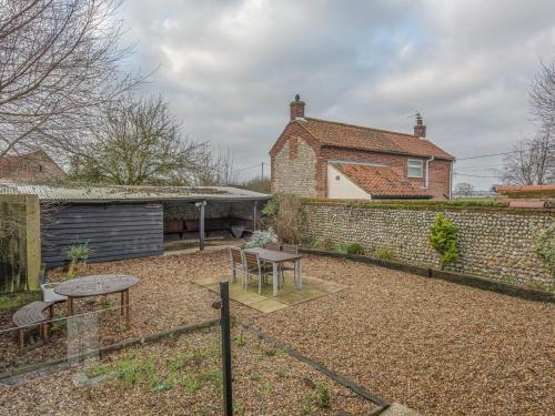 a backyard with a brick wall and a table at Flint Barn in North Walsham