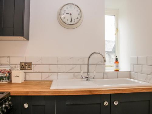 uma cozinha com um lavatório e um relógio na parede em The Hayloft em Oswestry