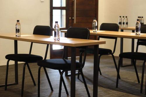 una fila de mesas de madera con sillas y botellas de vino. en Copperwood Hotel and Conferencing, en Brits