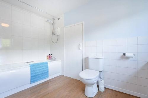 a white bathroom with a toilet and a bath tub at Rocking Chair Farmhouse in Alnwick