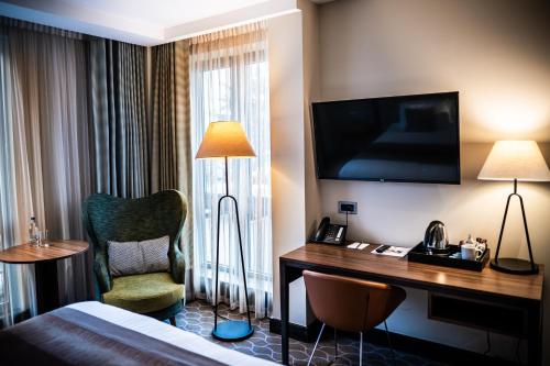 a hotel room with a bed and a desk and a chair at The Warwickshire Hotel and Country Club in Warwick