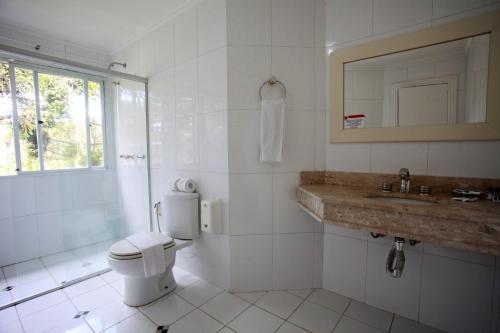 a white bathroom with a toilet and a sink at Sky Ville Hotel Canela in Canela