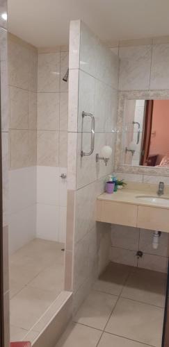 a bathroom with a shower, sink, and mirror at Hotel Costa Pacifico in Arica