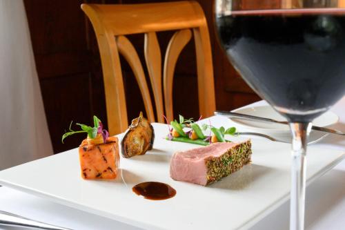 a white plate with food and a glass of wine at Romantik Hotel & Restaurant Sternen in Kriegstetten