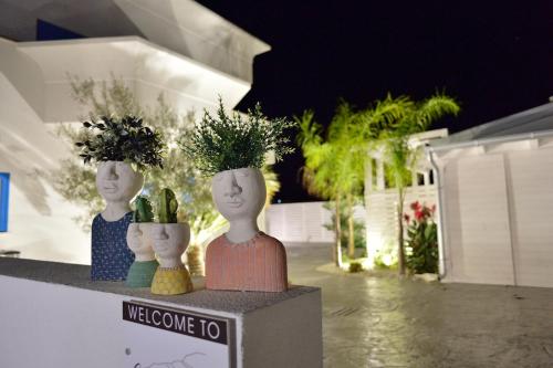 three statues of people with potted plants on a ledge at Scala dei Turchi Luxury Home in Realmonte