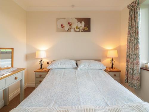 a bedroom with a bed with two lamps and a window at Little Lanes in Camelford