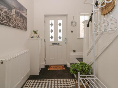 einen Flur mit einer weißen Tür und einer Treppe in der Unterkunft Cosy Coast Cottage in Bridlington