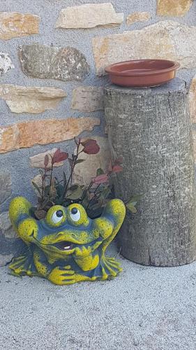 a yellow frog sitting on the ground next to a wall at CASA RURAL Arriaran in Leitza