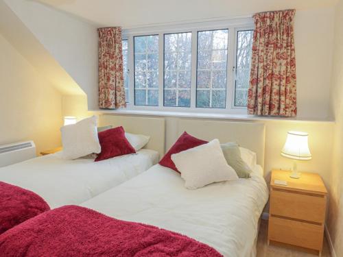 two beds in a room with two windows at Corner Cottage in Beaumaris