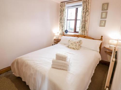a bedroom with a white bed with towels on it at The Stables in Llandyfrydog