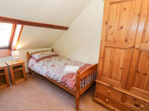 um quarto com uma cama e um armário de madeira em The Granary em Llandyfrydog