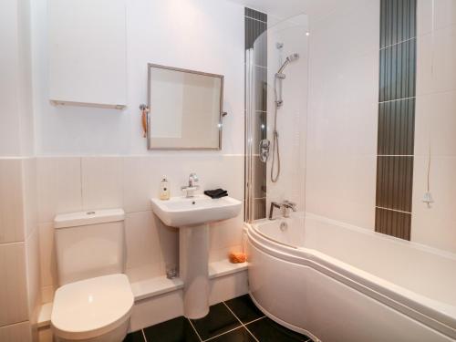 La salle de bains est pourvue d'un lavabo, de toilettes et d'une baignoire. dans l'établissement 10 Pen Llanw Tides Reach, à Rhosneigr