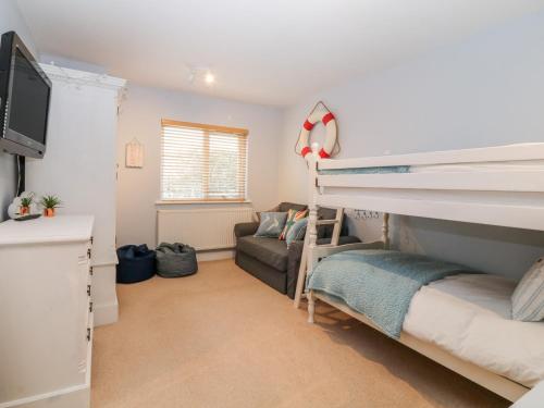a bedroom with a bunk bed and a couch at 10 Pen Llanw Tides Reach in Rhosneigr