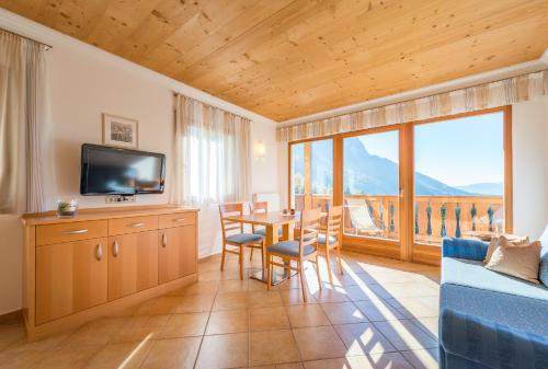 sala de estar con TV y mesa con sillas en Apartment Pircher 2, en Siusi