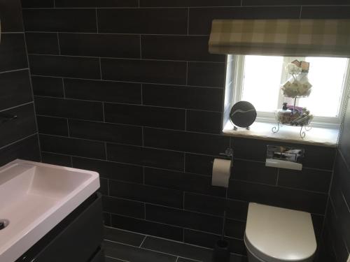 a black tiled bathroom with a toilet and a window at Hazel Manor in Harrogate