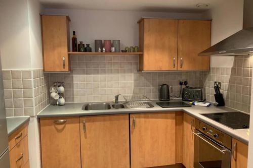 una cocina con armarios de madera y fregadero en Duke Street - Liverpool city centre apartment en Liverpool