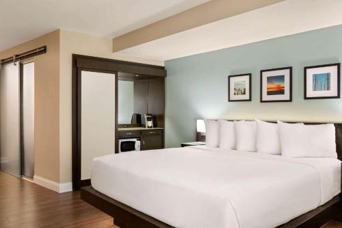 a bedroom with a large white bed and a kitchen at Wyndham Newport Hotel in Middletown