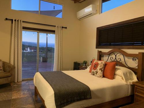 a bedroom with a bed and a large window at Villa Victoria in Valle de Guadalupe