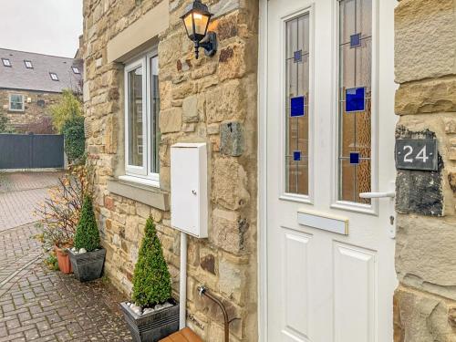 a white door of a stone house with two christmas trees at Allam Cottage in Barnard Castle