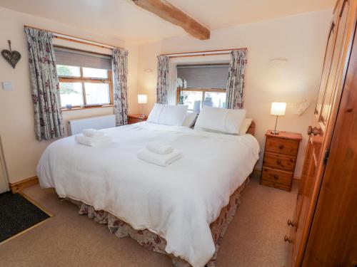 a bedroom with a large white bed with two towels on it at The Byre in Llandyfrydog