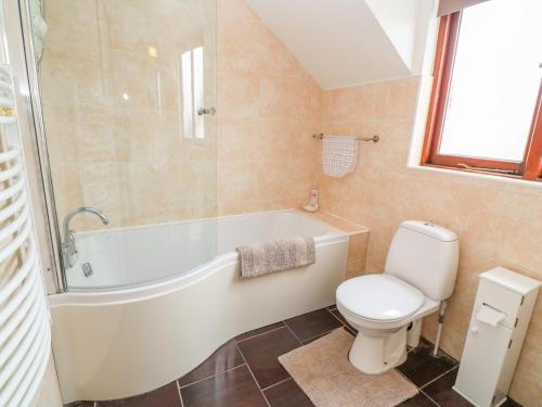 a bathroom with a white tub and a toilet at Mossley Cottage in Penzance