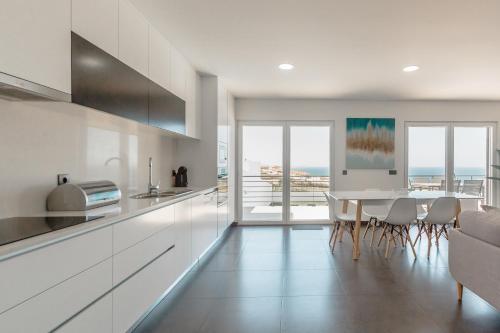 a kitchen with white cabinets and a table with chairs at Silver Villa in Lourinhã