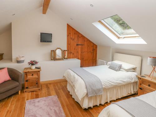 ein Schlafzimmer mit einem Bett, einem Sofa und einem Dachfenster in der Unterkunft Little Brook Cottage in Carmarthen