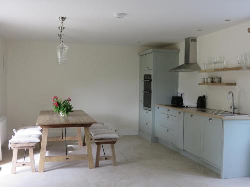 a kitchen with a wooden table and a kitchen with white cabinets at Old Village Barn in Woodford