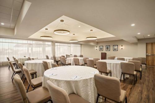 a room with white tables and chairs andwindows at Wyndham Newport Hotel in Middletown
