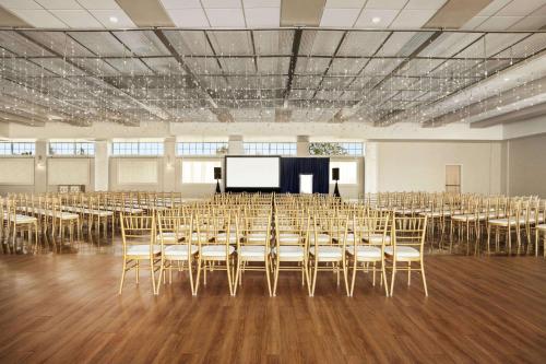 a room with a stage and chairs and a screen at Wyndham Newport Hotel in Middletown