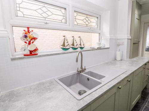 eine Küche mit einem Waschbecken und zwei Fenstern in der Unterkunft Twitcher's Rest in Hartlepool