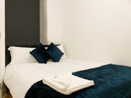 um quarto com uma cama branca e almofadas azuis em Cozy Nights - Ibrox Street em Glasgow