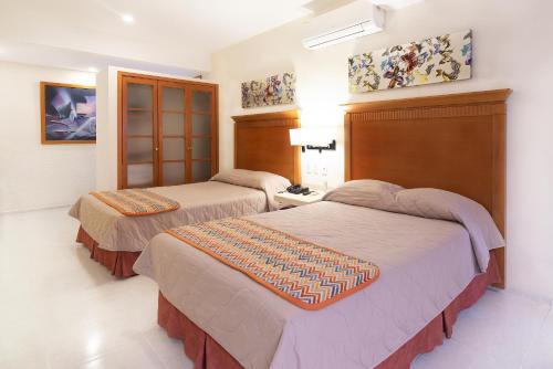 2 łóżka w pokoju hotelowym w obiekcie Hotel y Suites Nader w mieście Cancún