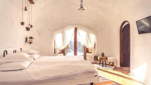 a bedroom with a white bed and a window at Pensiunea Dealul Verde in Porumbacu de Sus