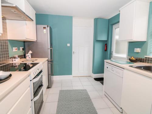 a kitchen with blue walls and white cabinets at Yr Adfa The Retreat in Blaenau-Ffestiniog