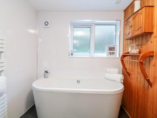 baño con bañera blanca y ventana en Polkirt Forge, en Mevagissey