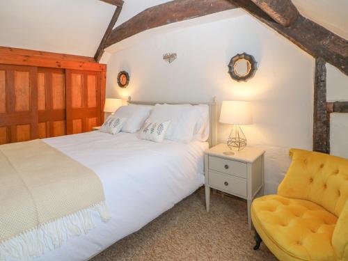 a bedroom with a white bed and a yellow chair at Dolphin House in Burford