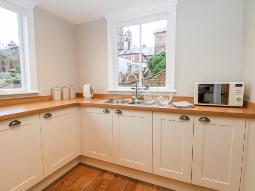 uma cozinha com um lavatório e um micro-ondas em South Tower Cottage em Macclesfield